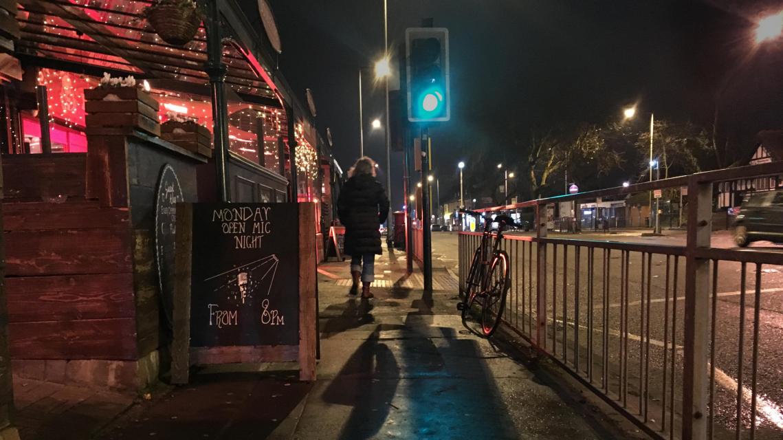 Night time street outside Strange Brew with A board advertising Open Mic.